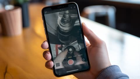 A close up of a mobile phone in someone's hand, with a vehicle health check report on screen