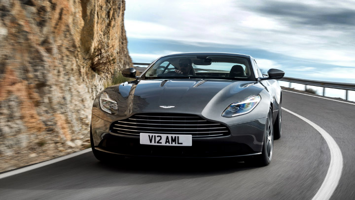 Aston Martin DB11 in grey driving on the road.