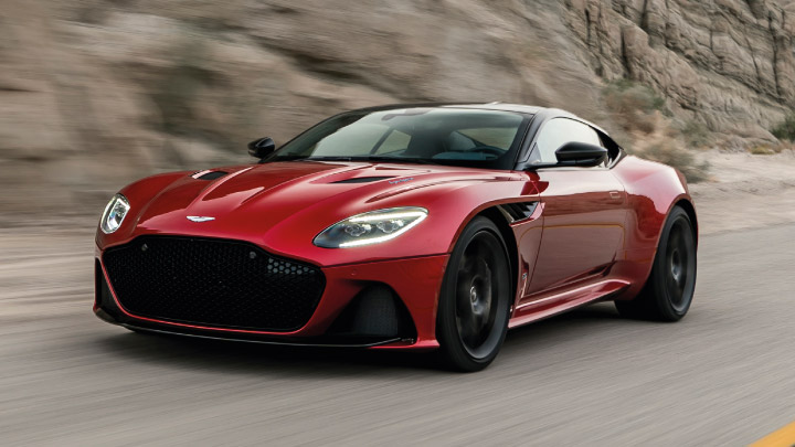 Aston Martin DBS in red driving on the road.