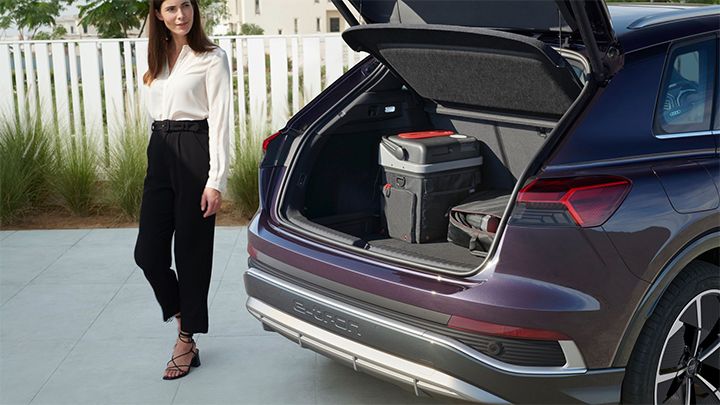 Woman walking past the open boot of an Audi with their accessories on display