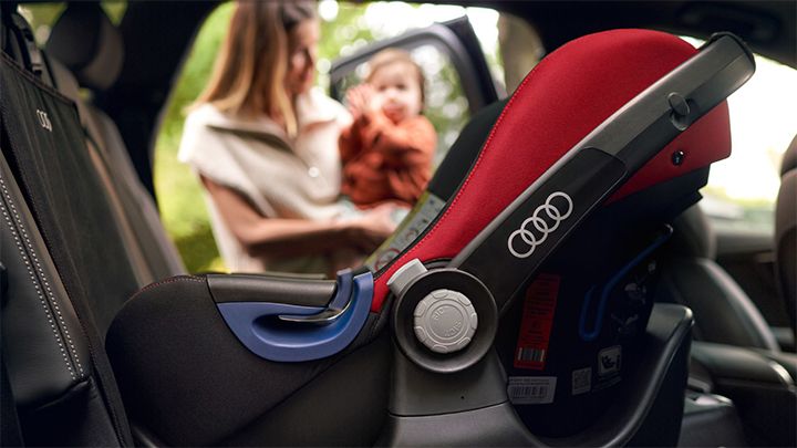 Close up of an Audi branded child seat and a woman with her child in the background