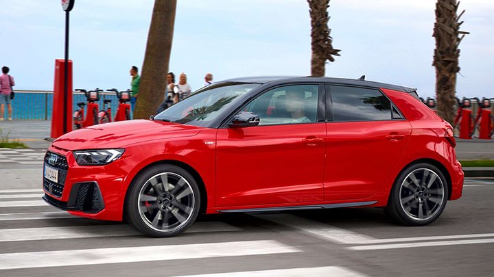 Lifestyle driving shot of a red Audi A1 Sportback driving down a coastal town road