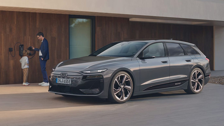 Dad and his son standing next to a grey Audi A6 Avant e-tron, ready to plug it in to charge