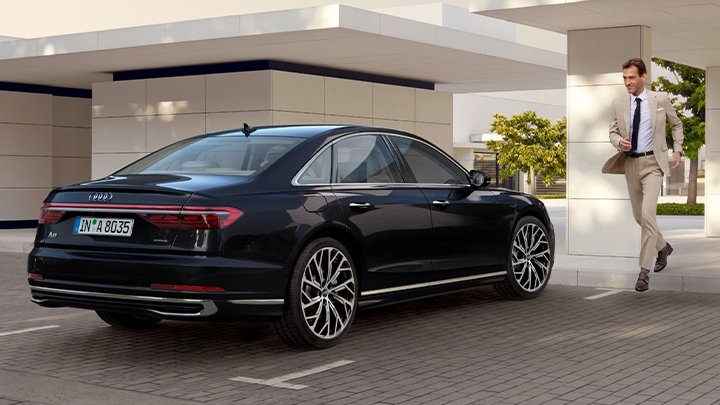 Rear lifestyle shot of a man walking down to a black Audi A8