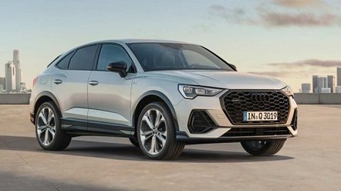 Front quarter shot of a silver Audi Q3 Sportback with a city background