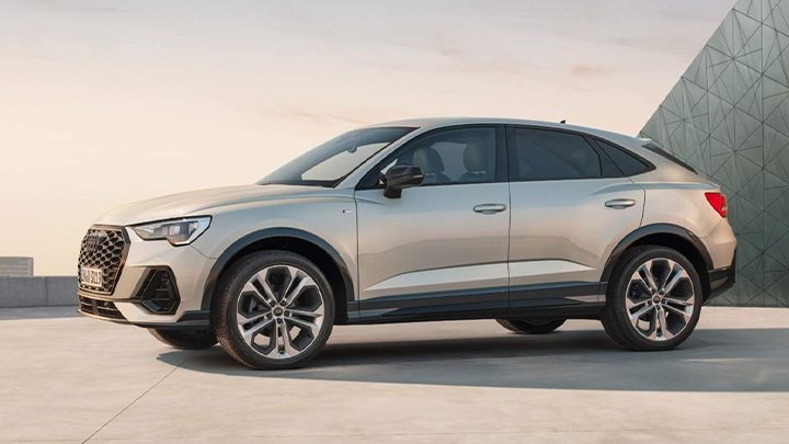 Side shot of a silver Audi Q3 Sportback with a city background