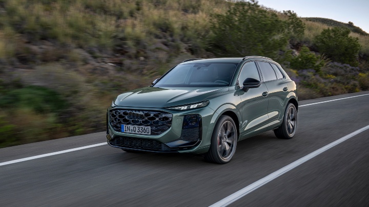 Green Audi Q3 SUV Driving along country road Front right angle