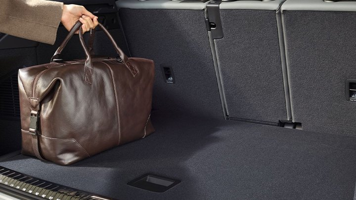 Close up of someone placing a brown duffle bag in the boot of an Audi Q3