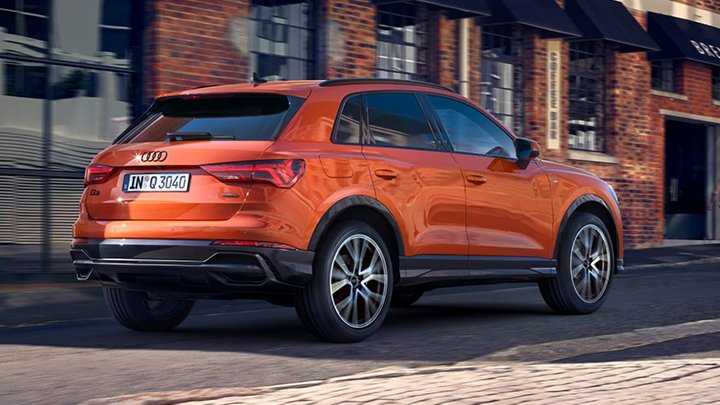 Rear quarter shot of a driving orange Audi Q3