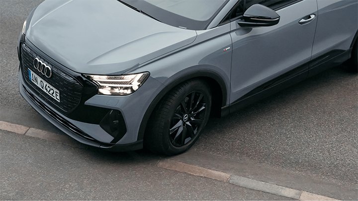 Aerial shot of a grey Audi Q4 e-tron's front left wheel, light and bonnet