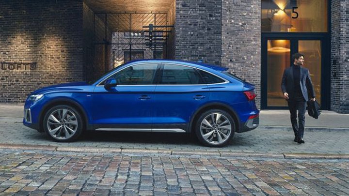Side shot of a blue Audi Q5 Sportback with a man walking to get into it