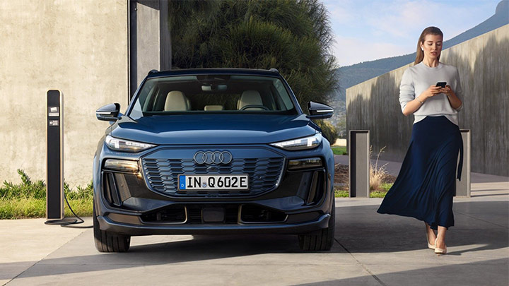Front shot of a blue Audi Q6 e-tron being placed on charge by the owner using the My Audi App