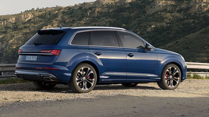 Rear quarter shot of a blue Audi Q7 with a green mountain background