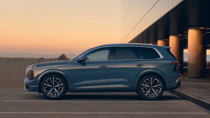 Audi Q7 side profile parked by modern building at sunset