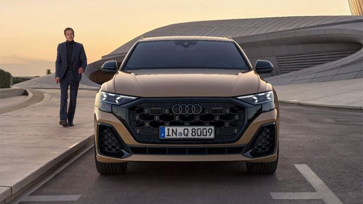 Front shot an Audi Q8 parked at sunset with a young man walking past