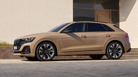 Side shot of a beige Audi Q8 parked in front of a building at sunset