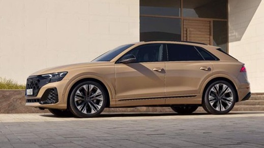 Side shot of a beige Audi Q8 parked in front of a building at sunset