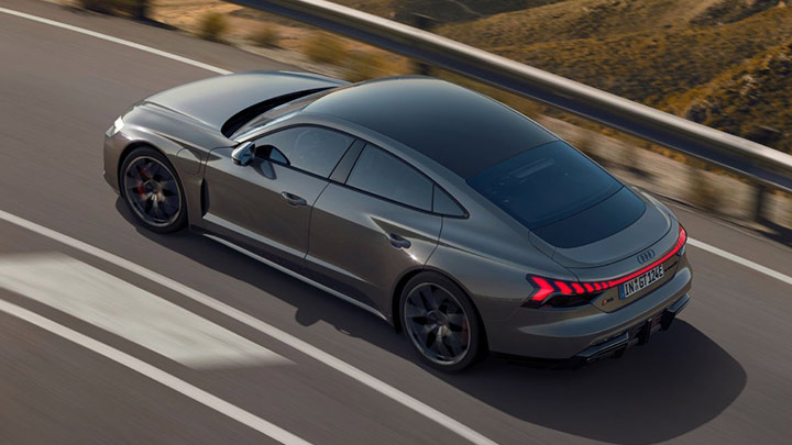 Aerial shot of a grey Audi RS e-tron GT driving down a road at sunset