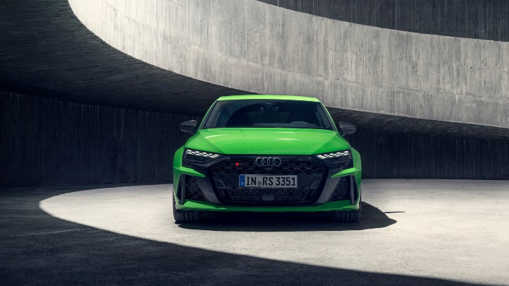 Front view of a green Audi RS 3 Sportback in a modern concrete architectural setting