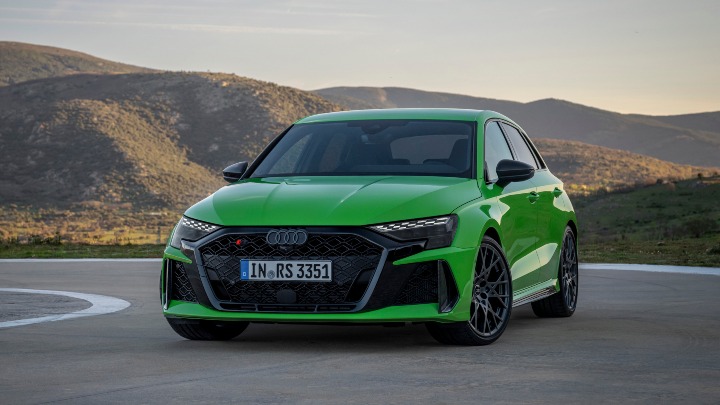 Green Audi RS 3 Sportback parked on an open mountain road with a scenic backdrop