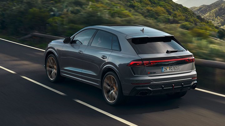 Rear of a grey Audi RSQ8 driving on the road with mountains to the right side