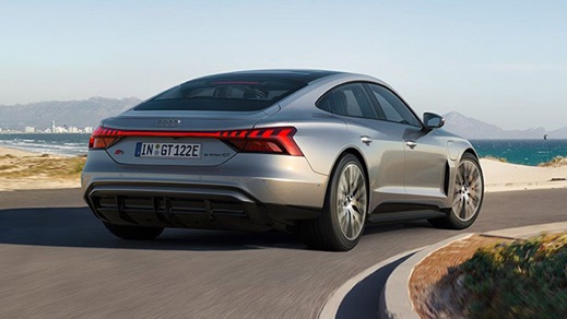 Back of grey Audi S e-Tron GT driving with mountains and ocean ahead