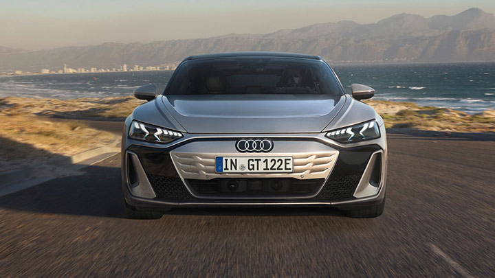 Front of a grey Audi S e-Tron GT driving in a mountain with ocean and city in the background