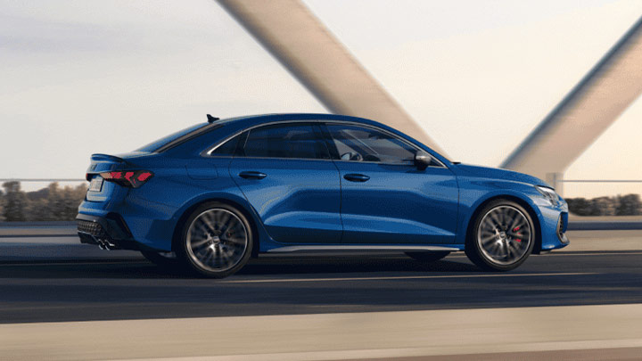 Side shot of a blue Audi S3 Saloon as it drives down a road