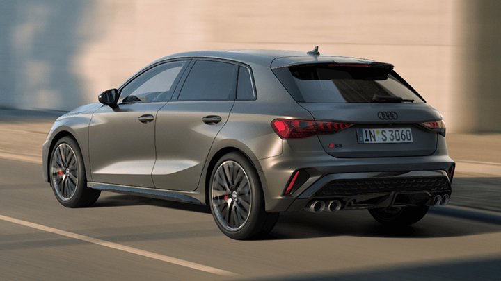 Back of the grey Audi S3 Sportback driving in front of a beige wall