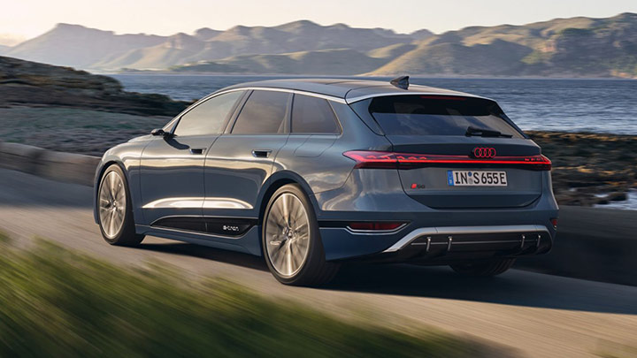 Back of a blue Audi S6 Avant e-Tron driving in the mountain with more mountains and the ocean in the background