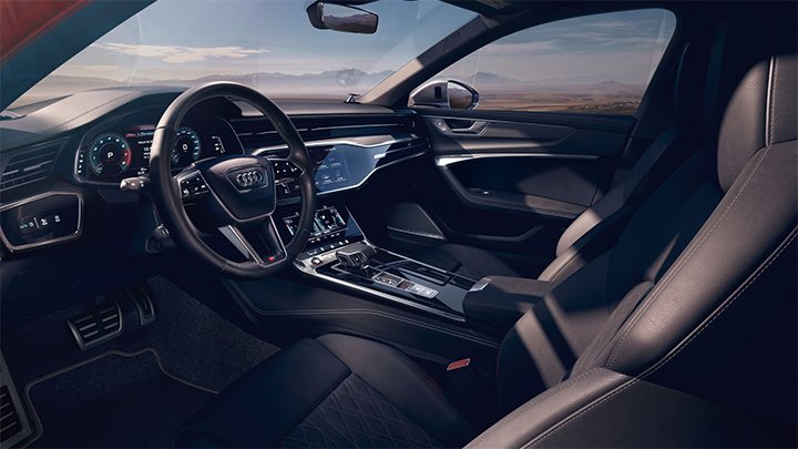 Cabin of an Audi S6 Saloon where you can see the steering wheel, the infotainment system and dark grey seats