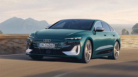 Front of green Audi S6 Sportback e-Tron driving in a rural area with mountains in the background
