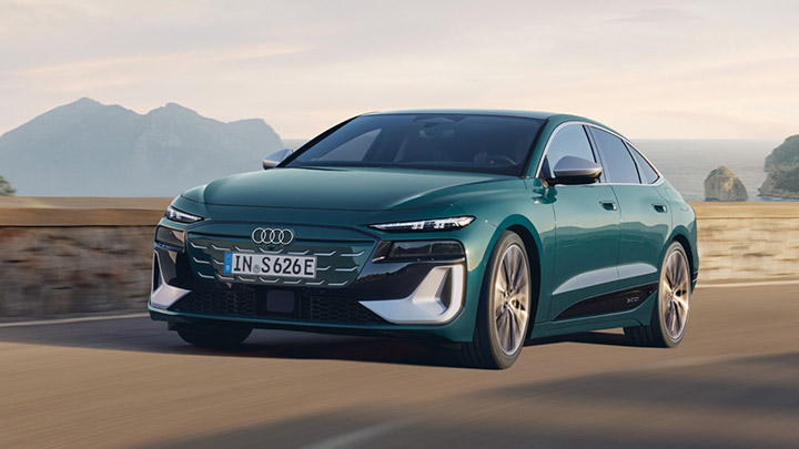 Front of green Audi S6 Sportback e-Tron driving in a rural area with mountains in the background