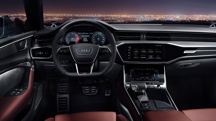 Cabin of an Audi S7 Sportback where you can see the steering wheel, the infotainment system and red seats
