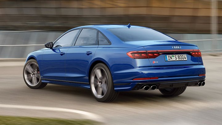 Back of blue Audi S8 driving on an asphalted road with grass on the left side