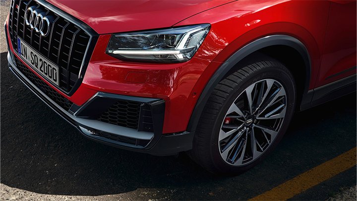 Zoomed in details of a red Audi SQ2 with the wheels, headlights and grille.