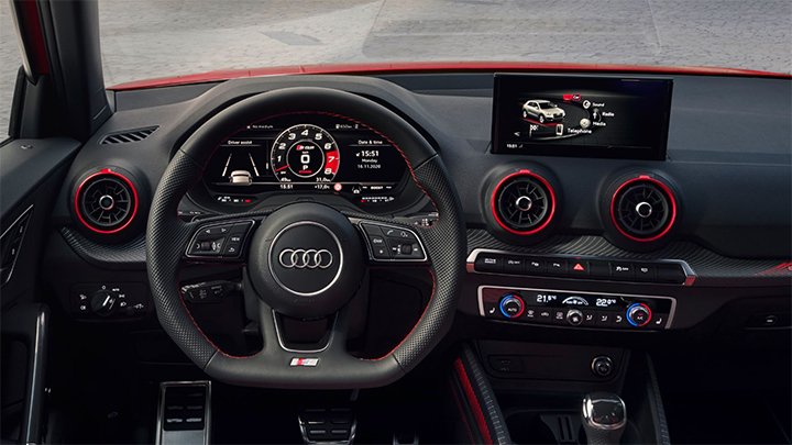 View of Audi SQ2 dashboard with the setting wheel, infotainment system and red detailings around the air conditioning