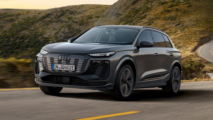 Grey Audi SQ6 e-Tron driving in an asphalted mountain with other mountains in the background