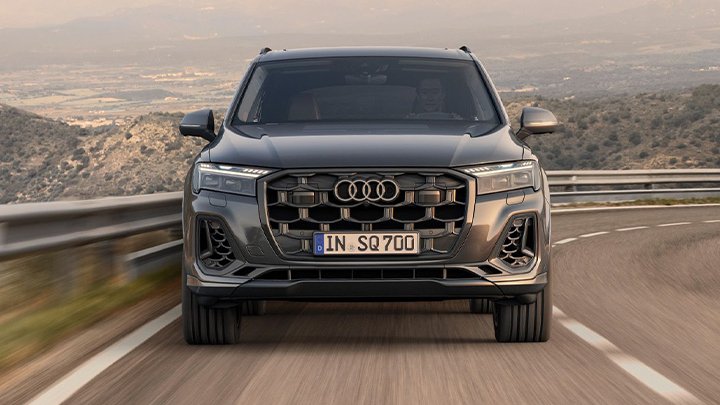 Grey Audi SQ7 Sportback driving in a asphalted mountain with other mountains in the background