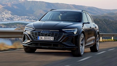 Black Audi SQ8 e-Tron driving in a mountain with several other mountains in the background and the ocean on the left
