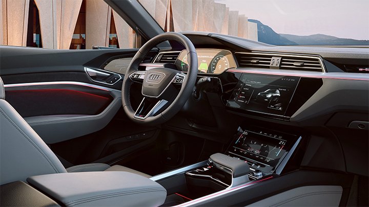 Cabin of an Audi SQ8 e-Tron where you can see the steering wheel, the infotainment system and grey seats
