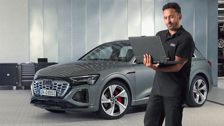 A technician standing in front of an Audi e-tron with a laptop