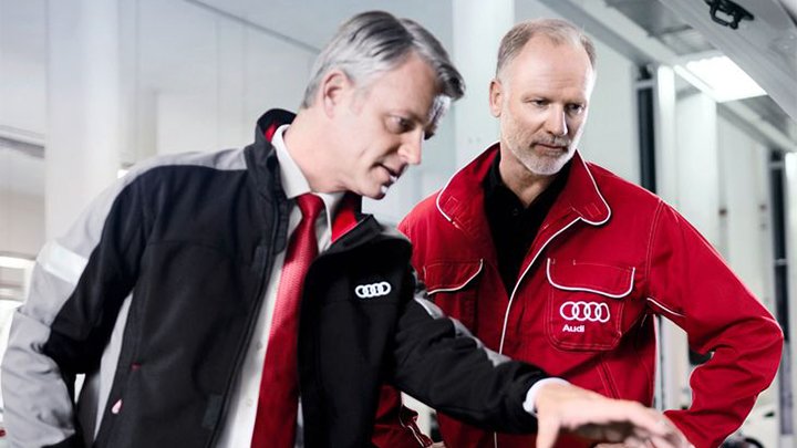 A service advisor and technician looking over the engine bay of an Audi