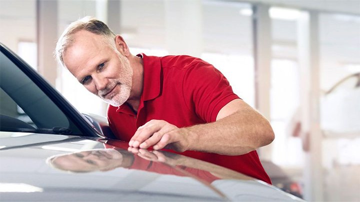 Middle aged Audi technician checking the condition of the bodywork on a car