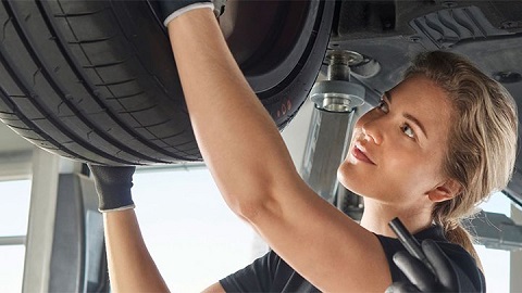 Young woman checking the condition of an Audi's tyre