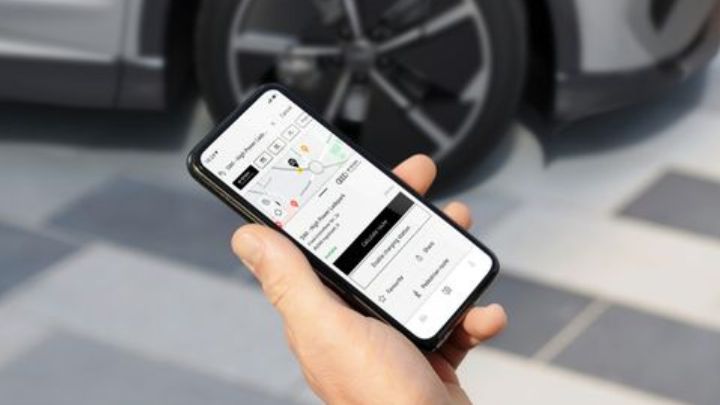 Man holding a smartphone with MyAudi app open in front of a silver Audi car