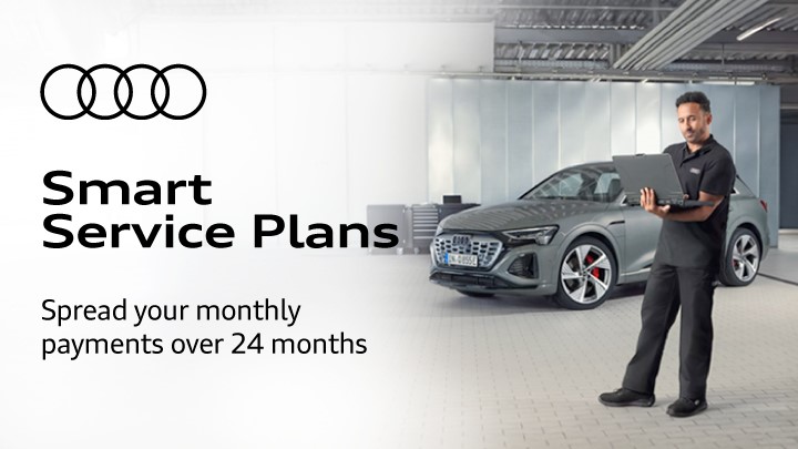 Man wearing grey uniform holding a laptop in front of an Audi vehicle