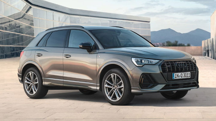Silver Audi Q3 parked in front of a modern looking building with glass walls