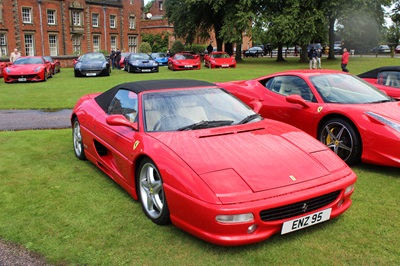 Red Ferrari F355 Spider parked on the grass.