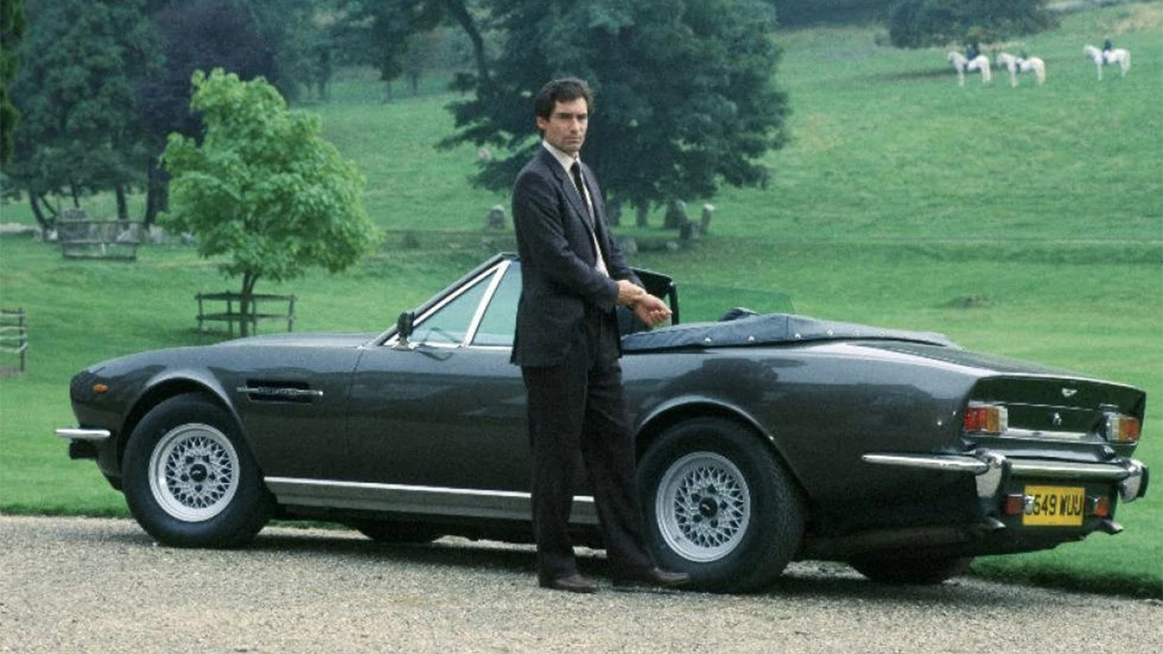 Timothy Dalton standing next to an Aston Martin Vantage Convertible